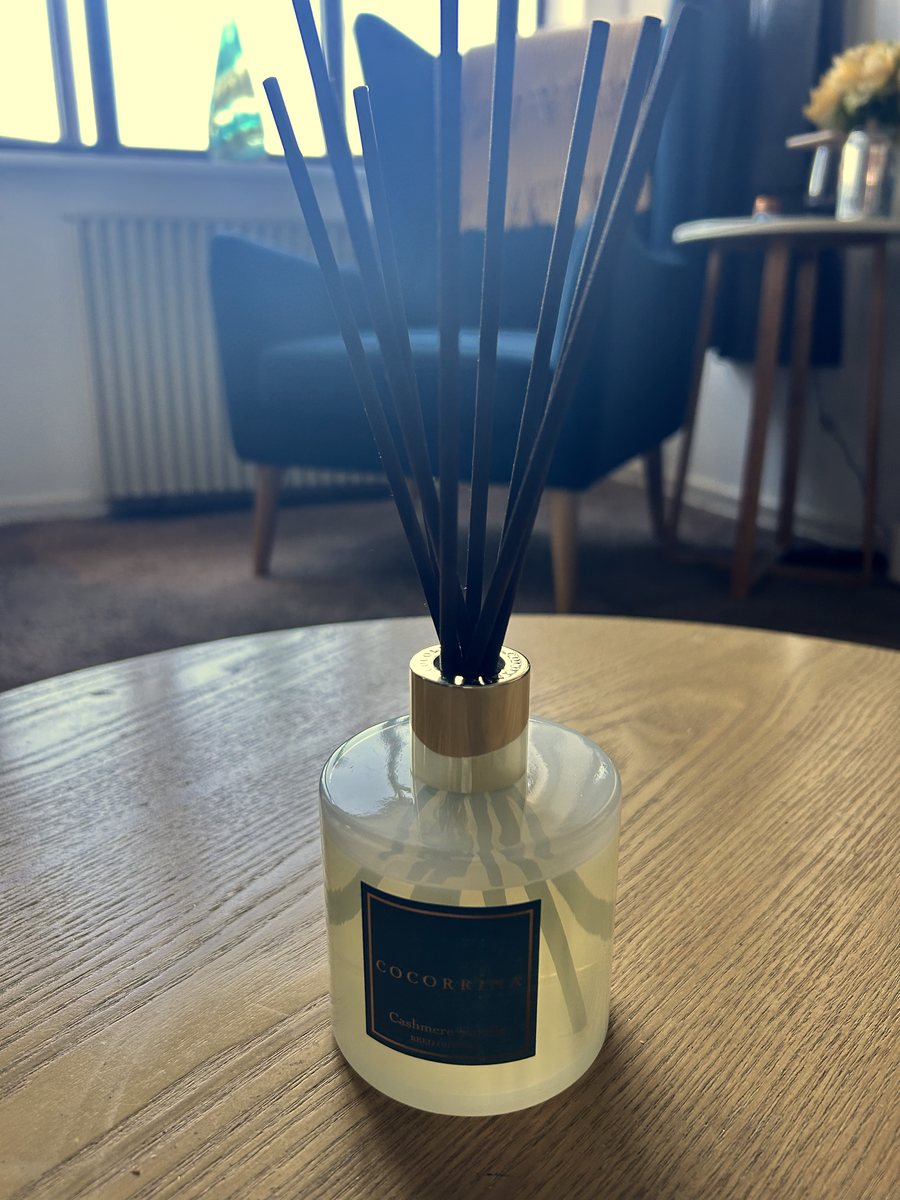 The Cocorrína Cashmere Vanilla reed diffuser set up with its reeds in, on a wooden table in a living room