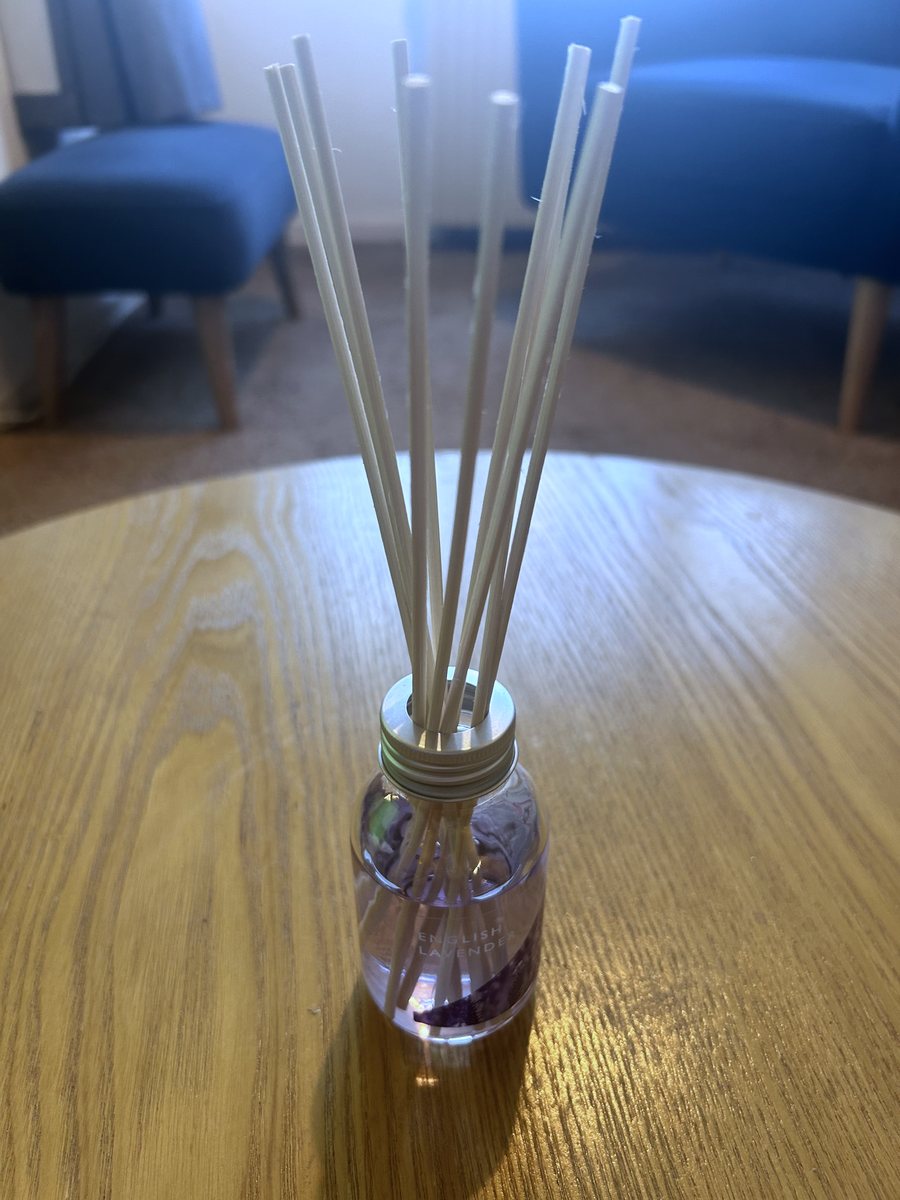 The Wax Lyrical English Lavender reed diffuser set up with its reeds in, on a wooden table in a living room